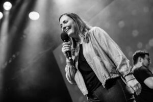 Slam Poetin mit Mikrofon auf der Bühne bei einem WoW Poetry Slam NRW vor Publikum